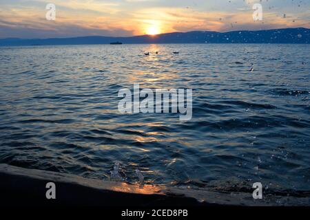 Wellen, die gegen einen Log auf Olchon Island, Baikalsee, Russland, bei Sonnenuntergang planschen Stockfoto