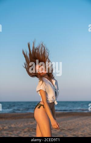 Entspannte, lebhafte Frau, die auf Strandsand steht Stockfoto