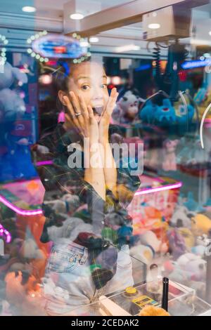 Schockierte Frau, die Spielzeug in Klauenmaschine ansieht Stockfoto