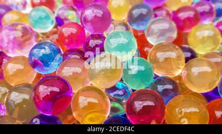 Viele verschiedene farbige Hydrogelkugeln. Set von mehrfarbigen orbis. Kristallwasserperlen für Spiele. Heliumballons. Kann als Hintergrund verwendet werden. Poly Stockfoto