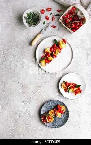 Oben Schuss der Teller mit gekocht gefüllten Tortellini garniert Mit Kräutern und Tomaten Stockfoto