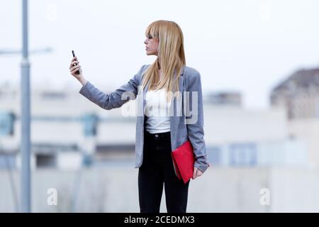 Junge blonde Dame bleibt und macht Selfie Stockfoto