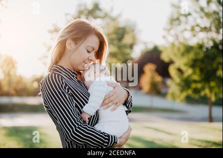 Junge Mutter umarmt sein Baby mit Down-Syndrom Stockfoto