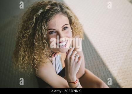 Porträt einer schönen jungen lockigen Frau mit hellen Lippen, die fröhlich auf die Kamera im Freien lächelt Stockfoto