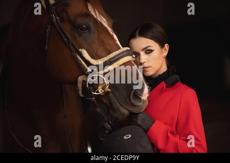 Frau Jockey Reiter umarmt braunes Pferd mit geschlossenen Augen. Konzept Liebe Tiere Stockfoto