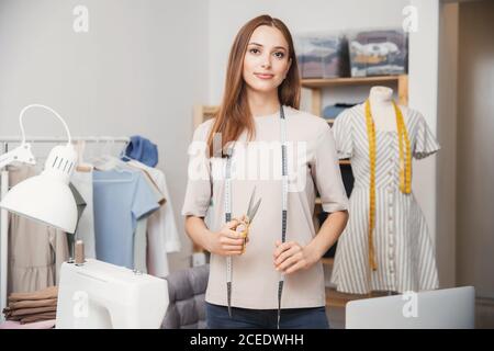 Professionelle Schneider junge Frau Designs hält Scheren Kleidung in Designer Werkstatt-Studio Stockfoto
