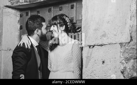Junge Braut und Bräutigam stehen zusammen in der Nähe der Wand Stockfoto