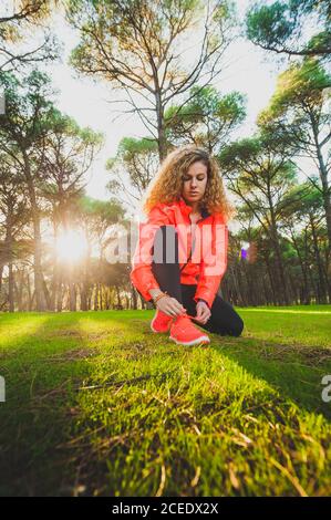 Frau bindet Schnürsenkel auf der Wiese im Sonnenlicht Stockfoto