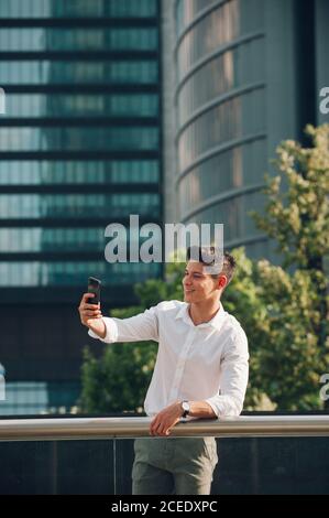 Junger Mann mit Smartphone auf Geländer gelehnt Stockfoto