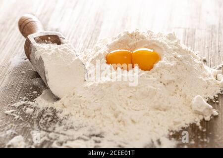Weizenmehl und Eier auf Backentisch bereit für die Zubereitung von Teigkuchen oder Pasta Stockfoto