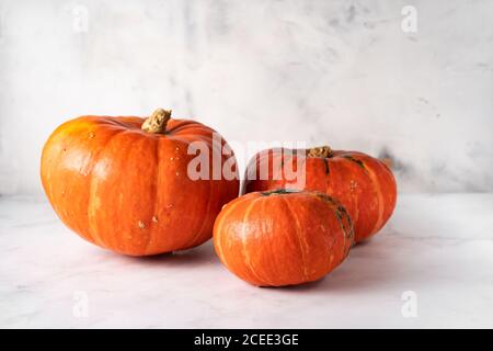 Drei orangefarbene Kürbisse mit unterschiedlicher Größe auf weißem Hintergrund Stockfoto