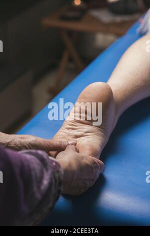 Therapeut tut Fußreflexzonenmassage auf Patienten. Behandlung, um schlechte Durchblutung auszugleichen Stockfoto