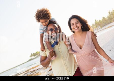 Glückliche ethnische Familie, die am Strand zusammen spazieren geht Stockfoto