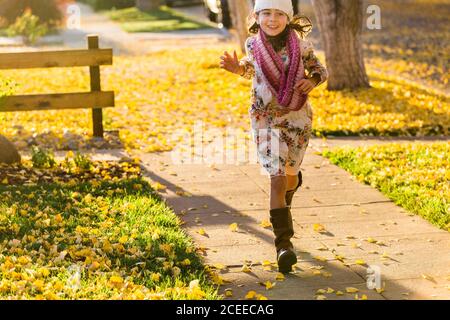 Mädchen läuft auf Gehweg zwischen gelben Blättern Stockfoto