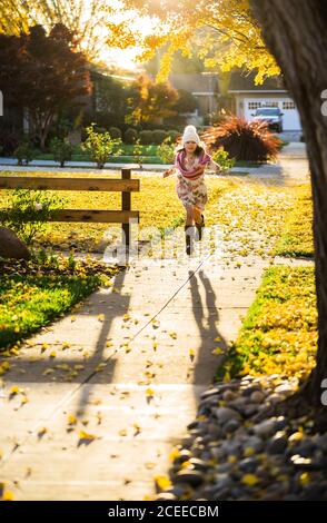 Mädchen läuft auf Gehweg zwischen gelben Blättern Stockfoto