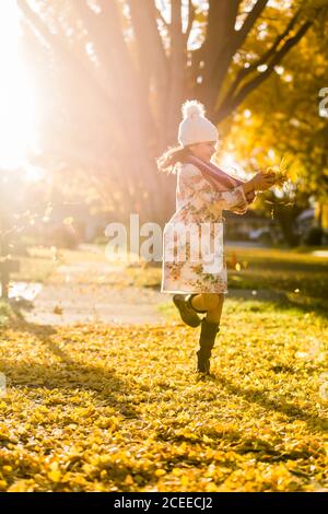 Mädchen läuft auf Gehweg zwischen gelben Blättern Stockfoto
