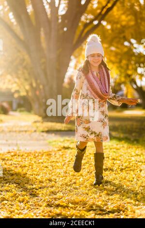 Mädchen läuft auf Gehweg zwischen gelben Blättern Stockfoto