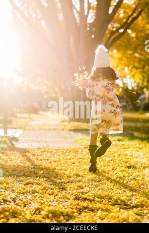 Mädchen läuft auf Gehweg zwischen gelben Blättern Stockfoto