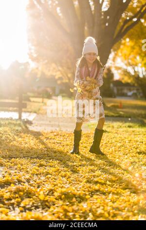 Mädchen läuft auf Gehweg zwischen gelben Blättern Stockfoto