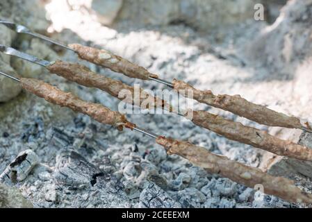 Nahaufnahme, Schweinefleisch lula Kebab auf Spieße, Grill Fleisch auf dem Grill, Lagerfeuer, Kohlen. Schädliche köstliche Speisen Stockfoto