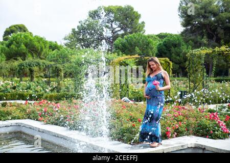 Schwanger attraktive Frau mit Blume in der Nähe von Brunnen Stockfoto