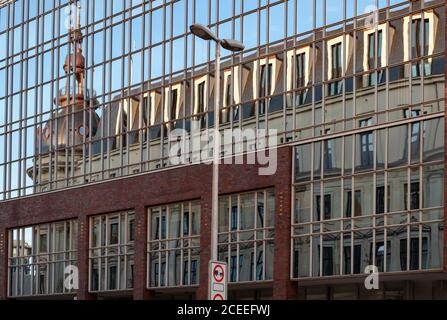 Verzerrte Spiegelung des historischen Gebäudes mit Kapellenturm in Glaswand reflektierende Oberfläche des modernen Gebäudes. Zeitgenössische und klassische Architektur Stockfoto