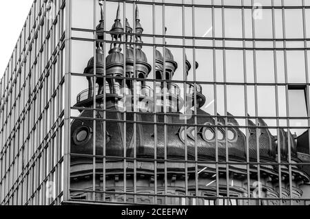 Spiegelung der Kapelle und Glockenturm in verspiegelter Wand. Verzerrte Reflexion in Glas-Panoramafenstern. Schwarzweiß-Foto des Firmengebäudes, ext Stockfoto