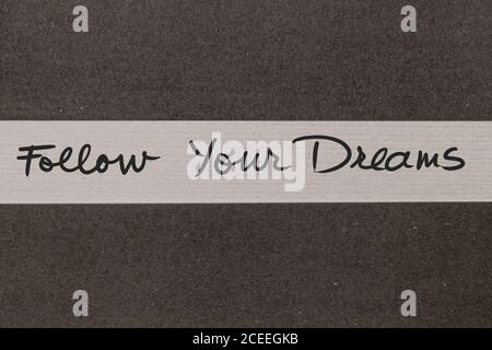 Weißer und grauer Papierhintergrund mit Follow Your Dreams Motivierende handgeschriebene Botschaft Stockfoto