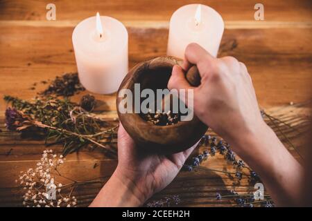 Mörser mit getrockneten Heilkräutern, Blumen und Kerzen, Vorbereitung zur rituellen Reinigung und Reinigung, weibliche Hände Stockfoto