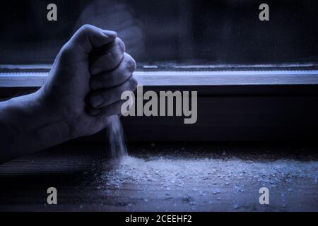 Hand Strewing Salz auf der Fensterbank, Ritual und Schutz für das Böse in die Nacht, mystische symbolische Stockfoto