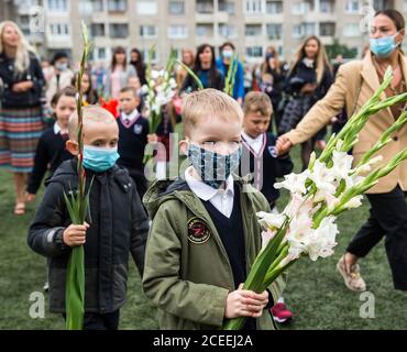 (200901) -- VILNIUS, 1. September 2020 (Xinhua) -- die Schüler nehmen am 1. September 2020 an der Eröffnungsfeier mit Blumensträußen in der Hand Teil, die den Beginn eines neuen Schuljahres am Gymnasium Vilnius Fabijoniskiu in Vilnius, Litauen, markiert. Litauens neues Schuljahr hat normal begonnen, aber Fernunterricht könnte in bestimmten Schulen wieder aufgenommen werden, wenn sie zu COVID-19 Hotspots werden. (Foto von Alfredas Pliadis/Xinhua) Stockfoto