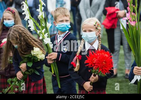 (200901) -- VILNIUS, 1. September 2020 (Xinhua) -- die Schüler nehmen am 1. September 2020 an der Eröffnungsfeier mit Blumensträußen in der Hand Teil, die den Beginn eines neuen Schuljahres am Gymnasium Vilnius Fabijoniskiu in Vilnius, Litauen, markiert. Litauens neues Schuljahr hat normal begonnen, aber Fernunterricht könnte in bestimmten Schulen wieder aufgenommen werden, wenn sie zu COVID-19 Hotspots werden. (Foto von Alfredas Pliadis/Xinhua) Stockfoto