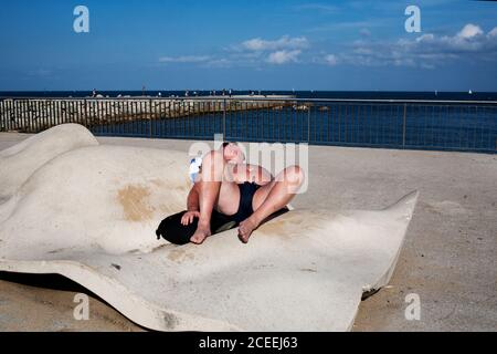 Reifer Mann liegt am Strand und Sonnenbaden auf dem Hintergrund des Meeres. Stockfoto