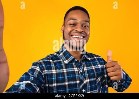 African American Guy Gesturing Thumbs-Up Machen Selfie Über Gelben Hintergrund Stockfoto