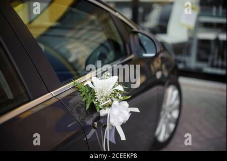 Schwarzer Körper Auto mit Blumen und Bögen Dekorationen für die Hochzeit. Stockfoto