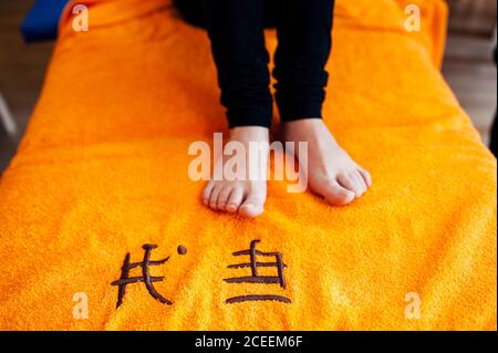 Beine einer nicht erkennbaren Frau, die auf dem Handtuch auf der Couch im Salon sitzt. Stockfoto