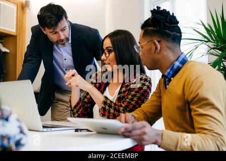 Männer und Frauen mit unterschiedlichen Rassen, die im Büro am Laptop sitzen und zusammenarbeiten. Stockfoto