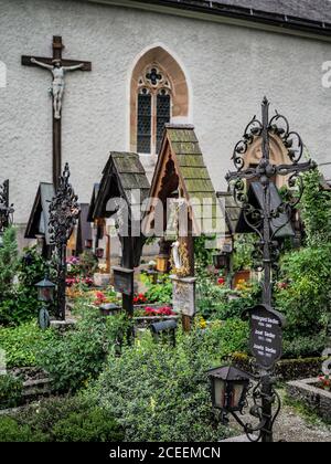 HALLSTATT, ÖSTERREICH - 06/15/2019: Der Friedhof in Hallstatt mit verschwommenem Berghintergrund. Salzkammergut. Stockfoto