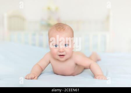 Niedliche liebenswert kaukasischen kleinen 5 Monate alten Baby Junge auf Bauch im Kinderzimmer mit Spaß spielen und lächeln liegen. Glückliches gesundes Neugeborenes Stockfoto