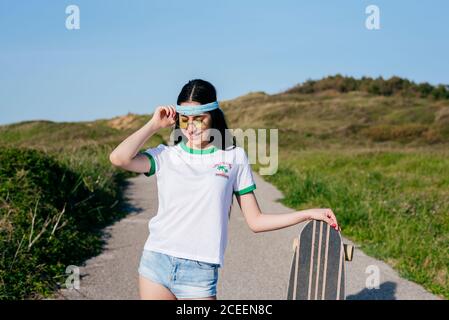 Stilvolle Teenager-Mädchen mit langen Bord im Sommer Stockfoto