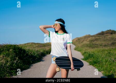 Stilvolle Teenager-Mädchen mit langen Bord im Sommer Stockfoto