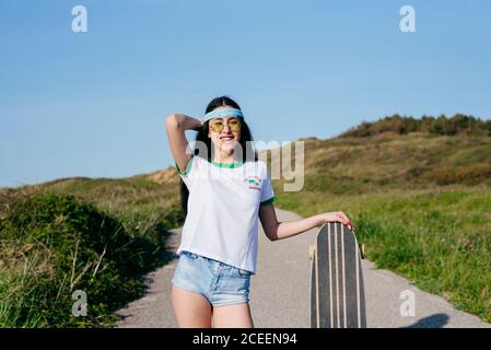Stilvolle Teenager-Mädchen mit langen Bord im Sommer Stockfoto