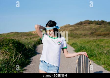 Stilvolle Teenager-Mädchen mit langen Bord im Sommer Stockfoto