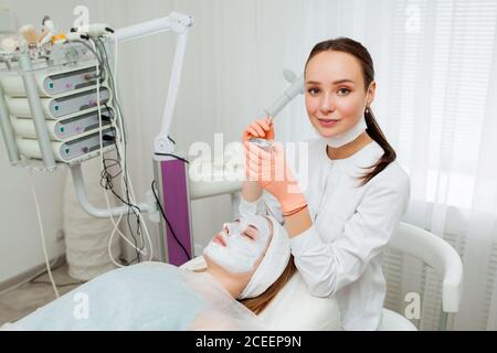 Kosmetologe Anwendung Maske auf das Gesicht des Kunden im Spa-Salon. Wellness-Center. Beruf im Gesundheitswesen Stockfoto