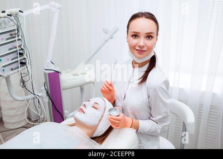 Kosmetologe Anwendung Maske auf das Gesicht des Kunden im Spa-Salon. Wellness-Center. Beruf im Gesundheitswesen Stockfoto