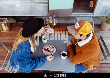 Junger Mann und Frau genießen leckeren Kuchen, während sie am Tisch in der Nähe von grungy van sitzen Stockfoto