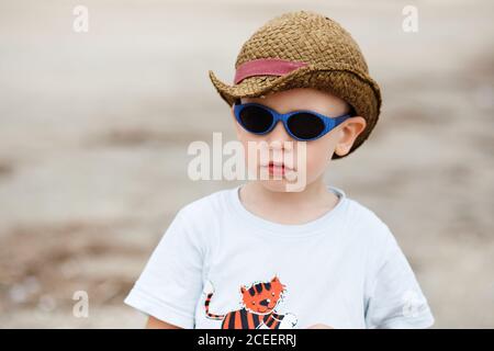 Kleiner Junge in Sonnenbrille und Hut im Freien Stockfoto