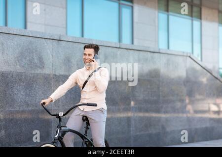 Kommunikation auf dem Smartphone während der Fahrt. Junger Geschäftsmann mit Fahrrad Stockfoto