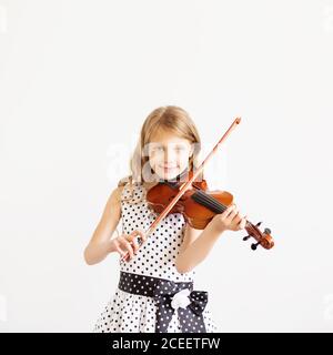 Portrait eines Mädchens mit Saite und Geige. Porträt des kleinen Geigers. Schönes begabtes kleines Mädchen, das auf Geige gegen die weiße BA spielt Stockfoto