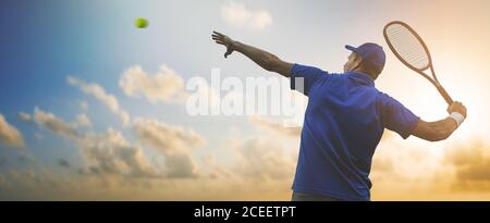 Professioneller männlicher Tennisspieler in blauem Hemd, der Ball mit Schläger auf Sonnenuntergang Himmel Hintergrund trifft. Banner Copy Space Stockfoto